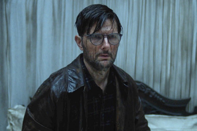 Adam Scott stands with dirt streaking down his face in a scene from HOKUM.