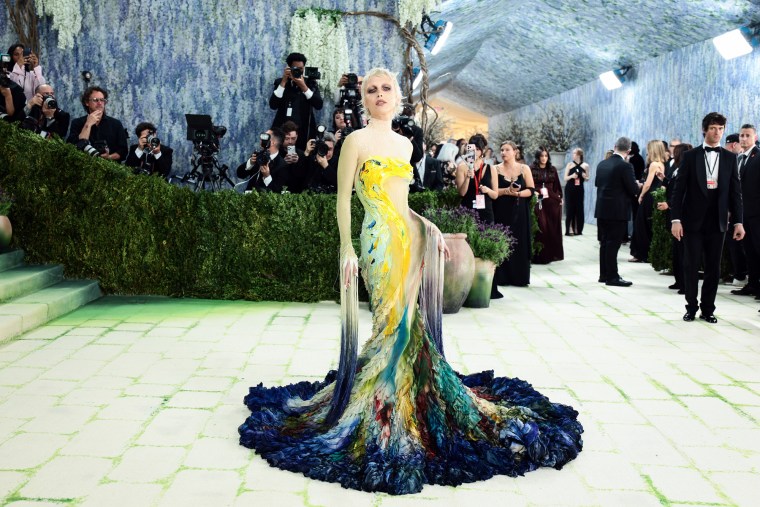 Emma Chamberlain at the Met Gala in a yellow blue and green floor length gown
