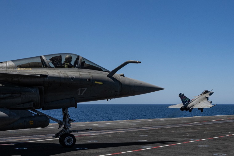Two fighter jets on the flight deck of an aircraft carrier.