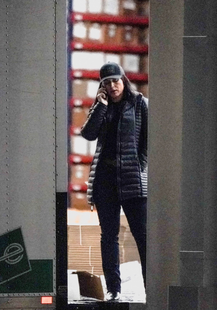 Tulsi Gabbard talking on the phone wearing a black ballcap and puffer jacket.