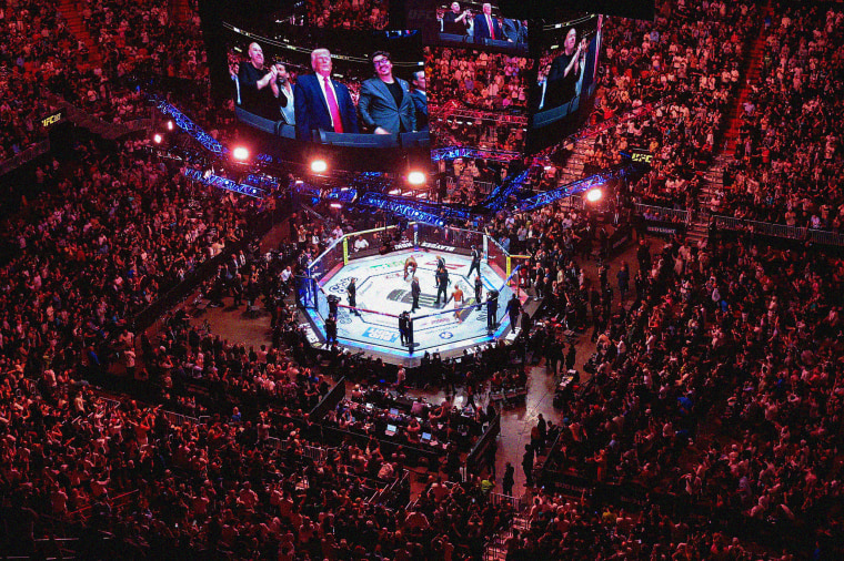 Aerial view of a stadium with a UFC ring and TV screens showing President Donald Trump, Dana White and Hunter Campbel.. 