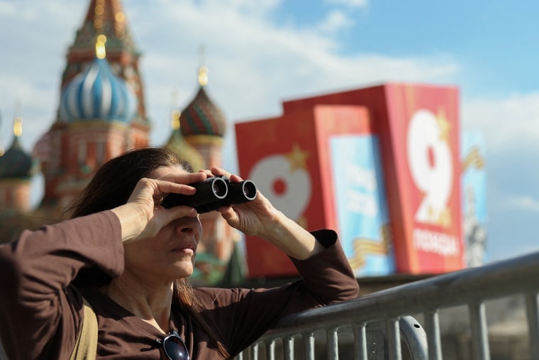 A tourist watches through binoculars at Red Square with St. Basil's Cathedral in the background in Moscow
