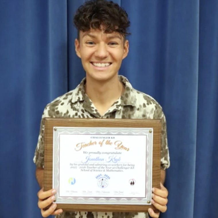 A young man holding an award certificate and smiling broadly.