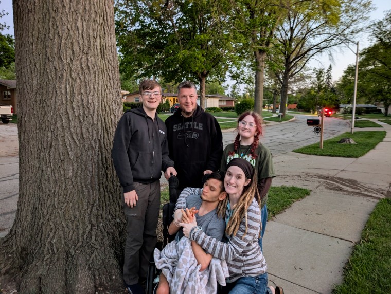 Anna Keyzer and family members pose by a tree on a sidewalk for a family portrait