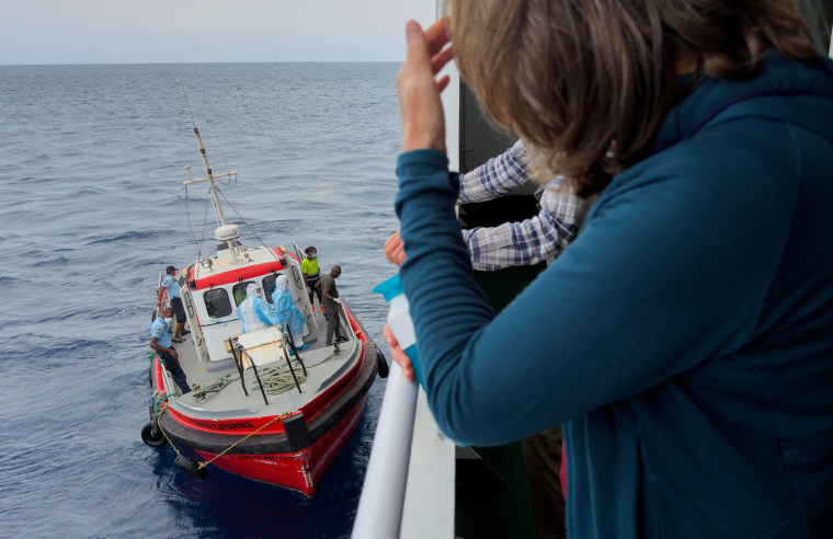 Passengers on the the hantavirus-stricken cruise ship, MV Hondius, watch epidemiologists board the boat