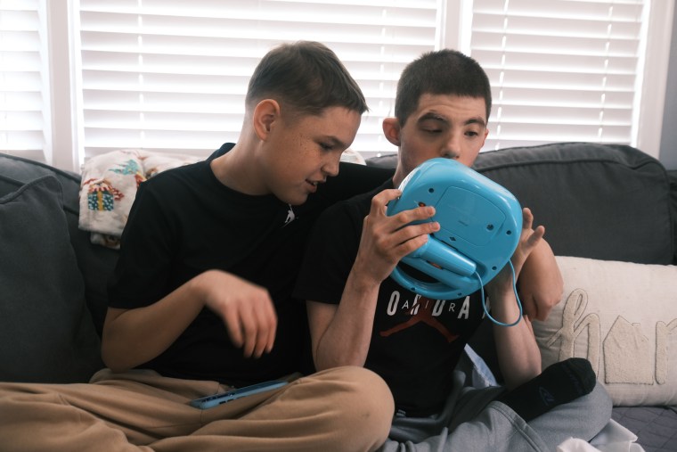 Jason, left, playing with a blue toy, sits next to his brother, 
