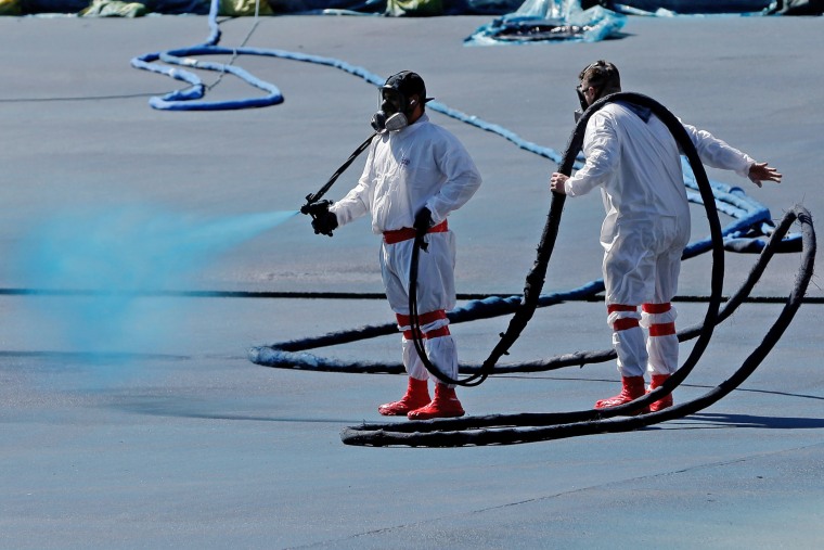 Workers apply a blue protective coating as part of a renovation project to the reflecting pool Friday, May 8, 2026, on the National Mall in Washington. 