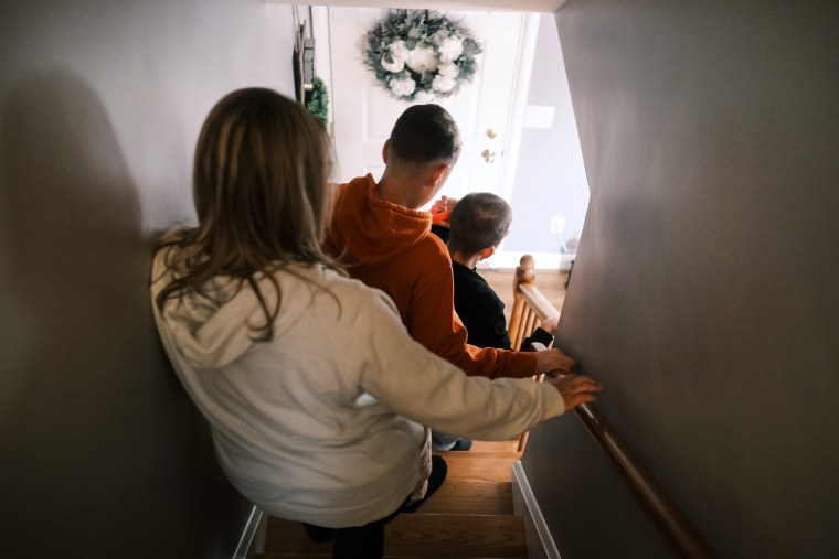 Melissa Gonce and her two sons walk down the stairs, seen from their backs
