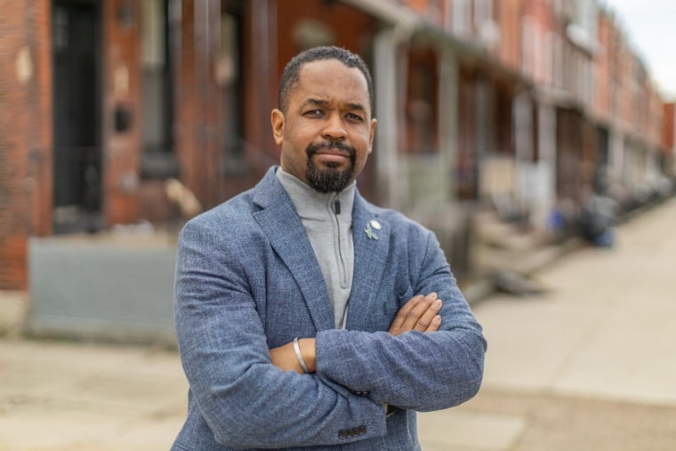 Sharif Street stands outside on a residential sidewalk and crosses him arms to pose for a portrait