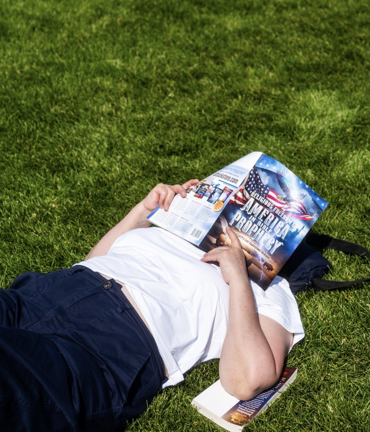 A man with a book over his face lying on the grass.