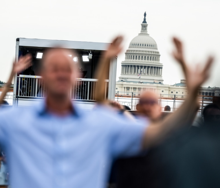 The U.S. Capitol building is visible behind a group of people praying