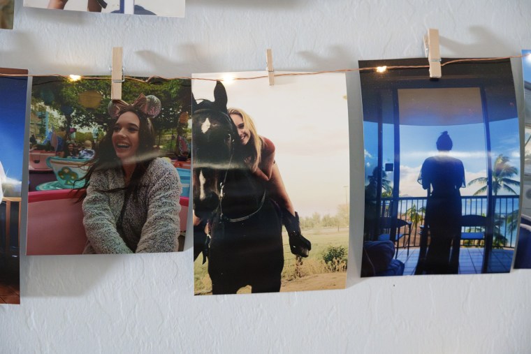 Three photos of a young woman are hung with mini clothespins from a wire of LED lights on a wall.