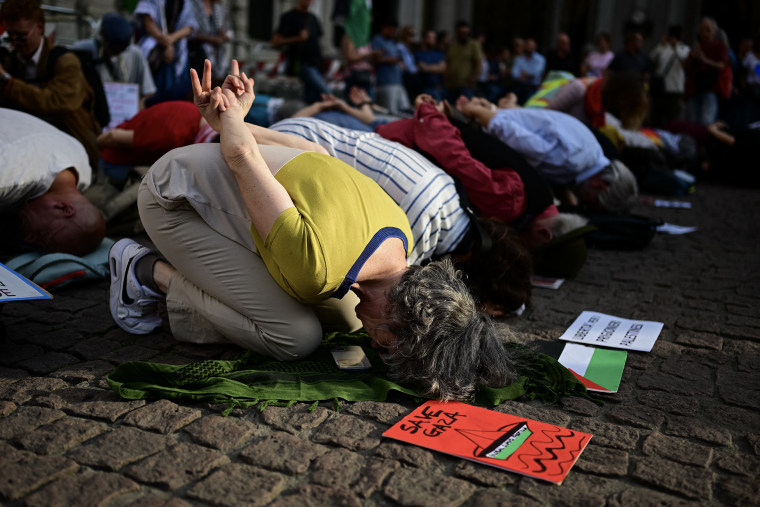 Numerous activists kneeling with their foreheads on the ground and their hands behind their backs.