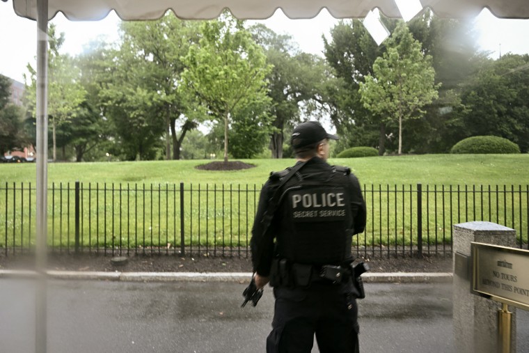 A secret Service agent holding a rifle on the grounds of the White House.
