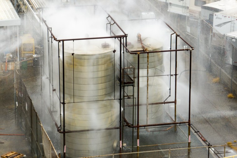 Steam and mist rising off of industrial tanks.