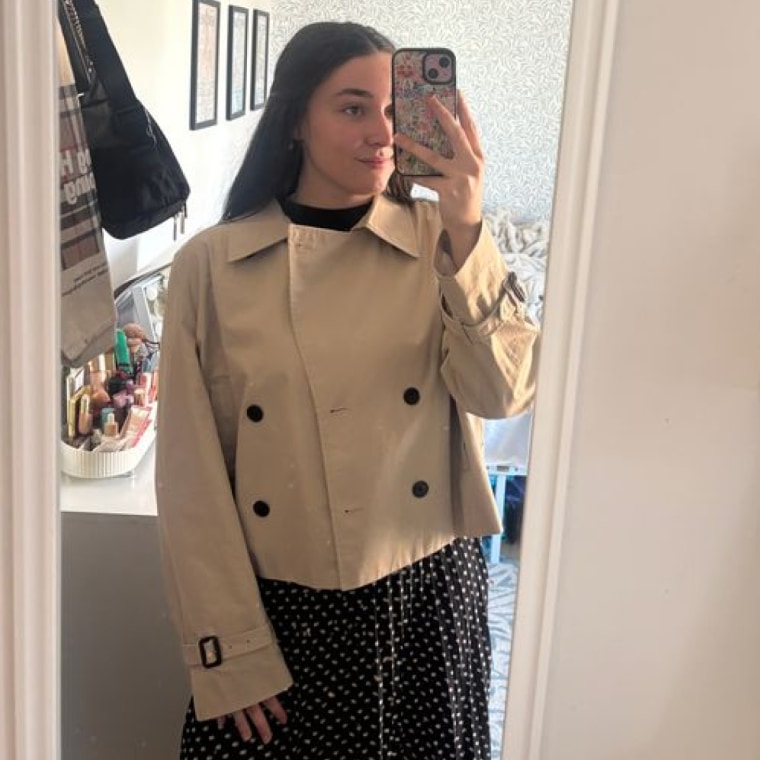 A woman standing in mirror wearing Aritzia The Esquire Short Trench Coat