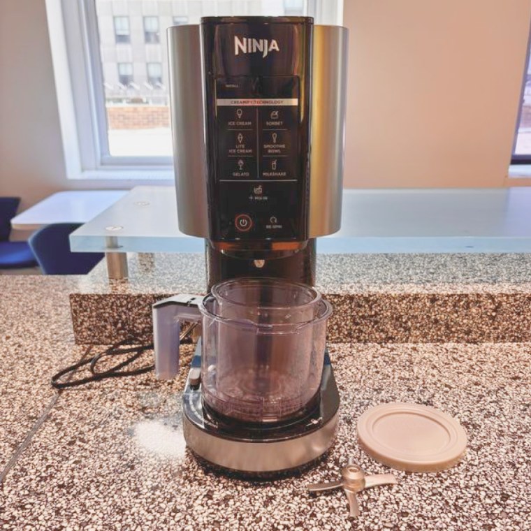The Ninja Creami on a granite table with the mixing paddle beside it.