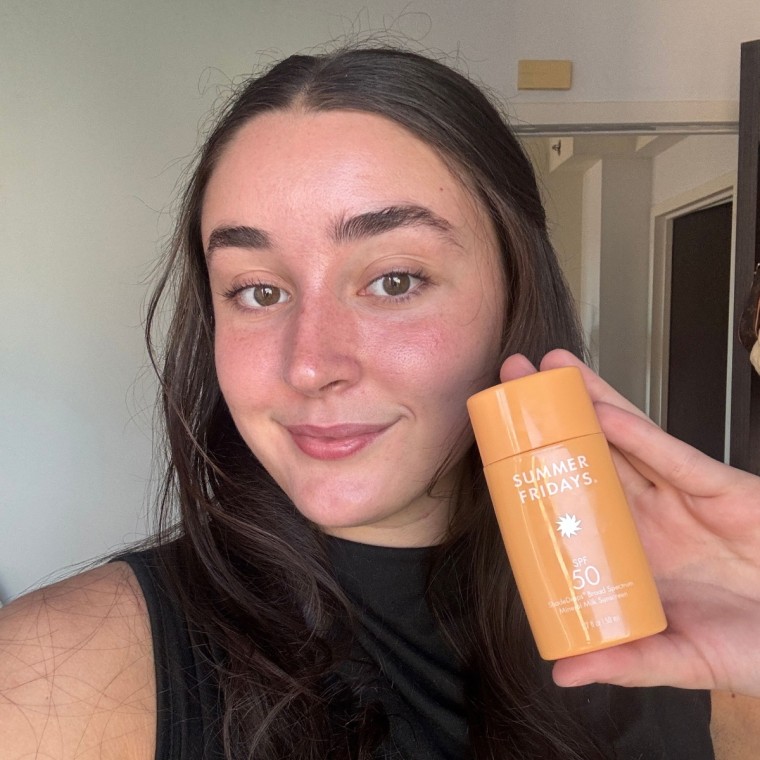 A person Holding up Summer Fridays ShadeDrops Broad Spectrum SPF 50 Mineral Sunscreen.