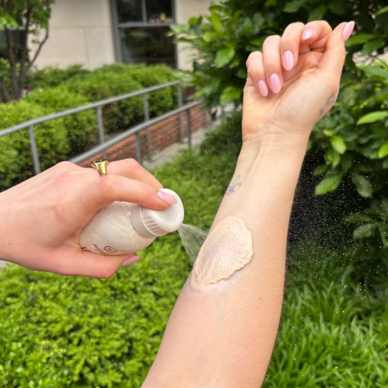 A woman applying Australian Gold’s SPF Tinted Mineral Sunscreen Spray.