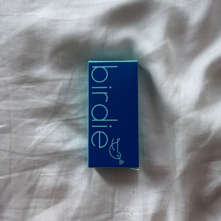 Photo of the Birdie Keychain packaging on a white bedsheet.