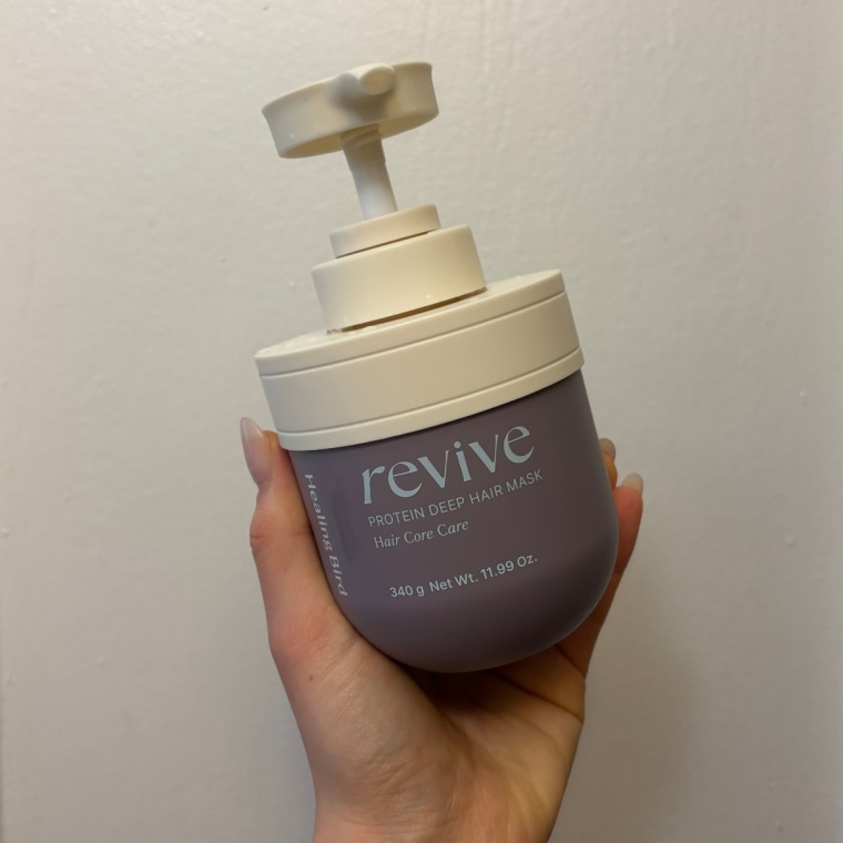Hand holding the Revive Protein mask against a white door.