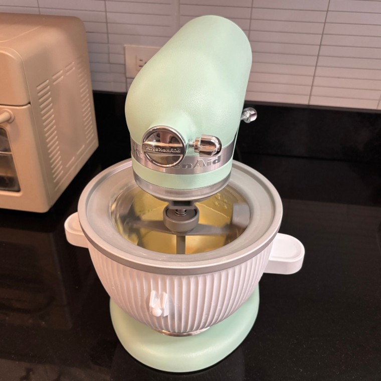 Light green KitchenAid Stand Mixer with ice cream maker attachment installed.