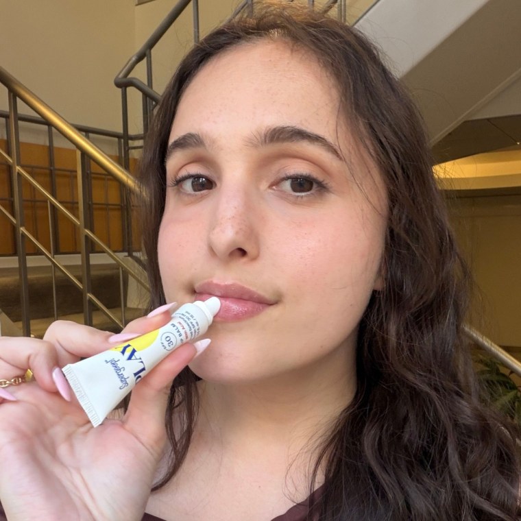 Woman applying Supergoop lip balm