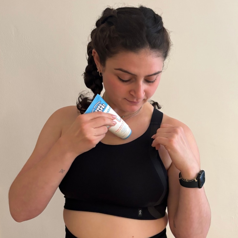 A woman applying Megababe’s Thigh Rescue Gel under her sports bra straps.