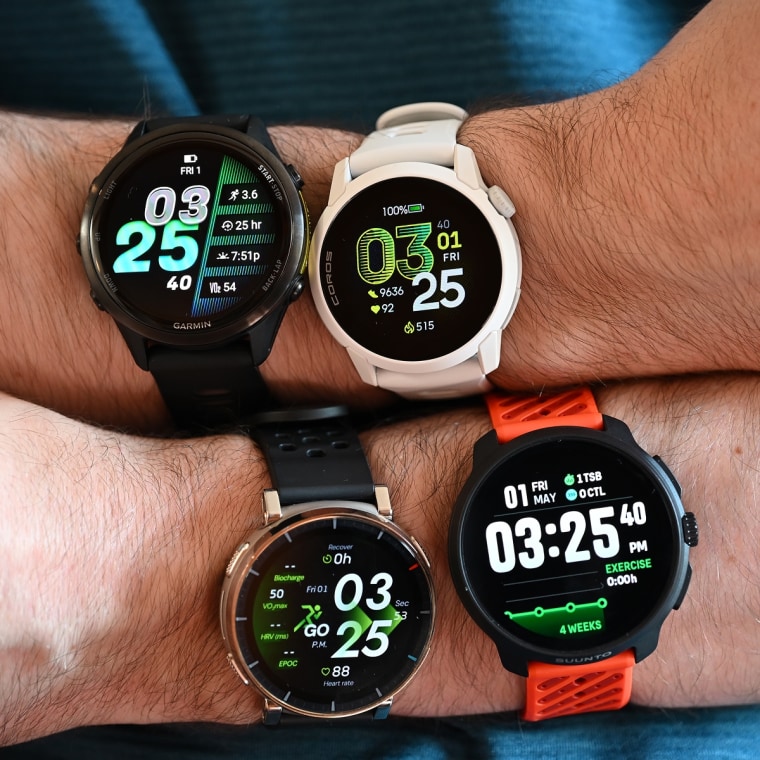 A close up of four different running watches on the wrists of the writer.