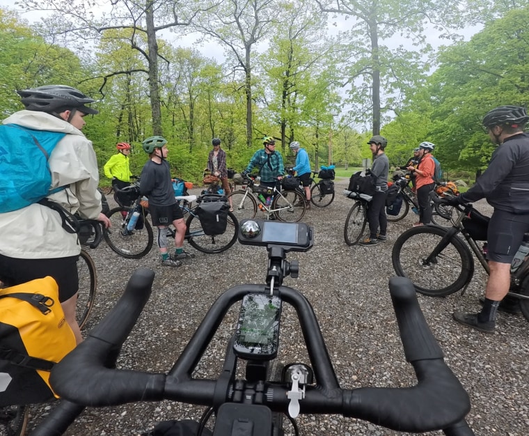 A group of cyclists with their bikes, standing in a rough circle.