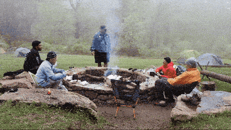 A timelapse of a group of people hanging out outdoors around a large stone fire pit.