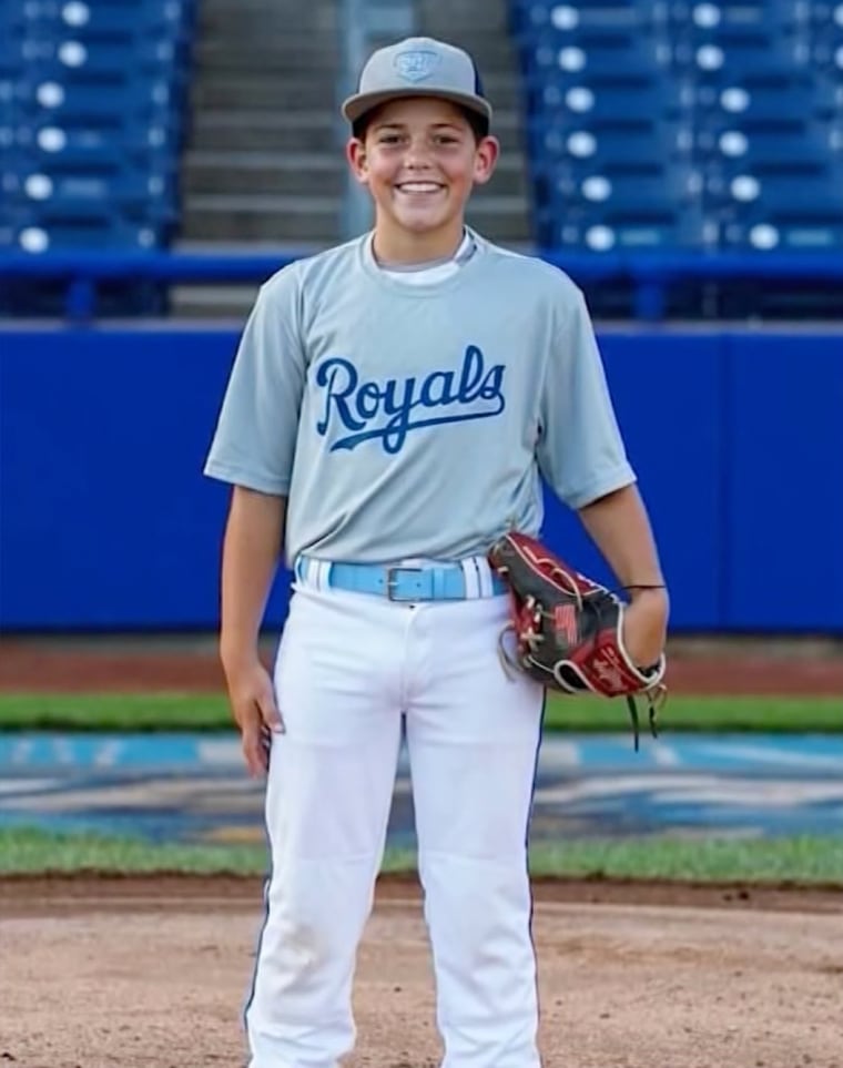 Xavier Taylor stands on a baseball field in a Royals uniform and wearing a baseball glove on one hand