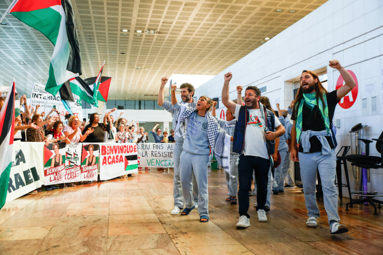 People raise their fists as they walk past a crowd carrying Palestinian flags