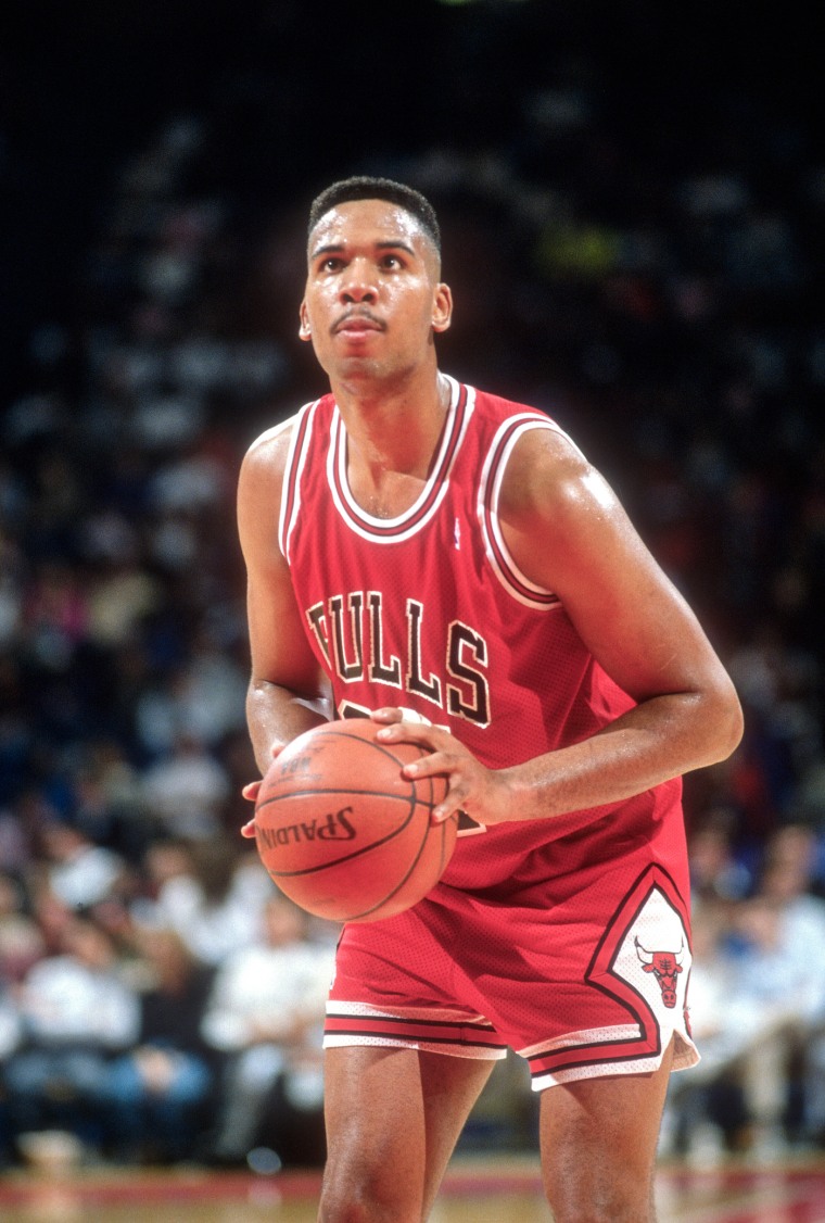Stacey King holds a basketball on the court