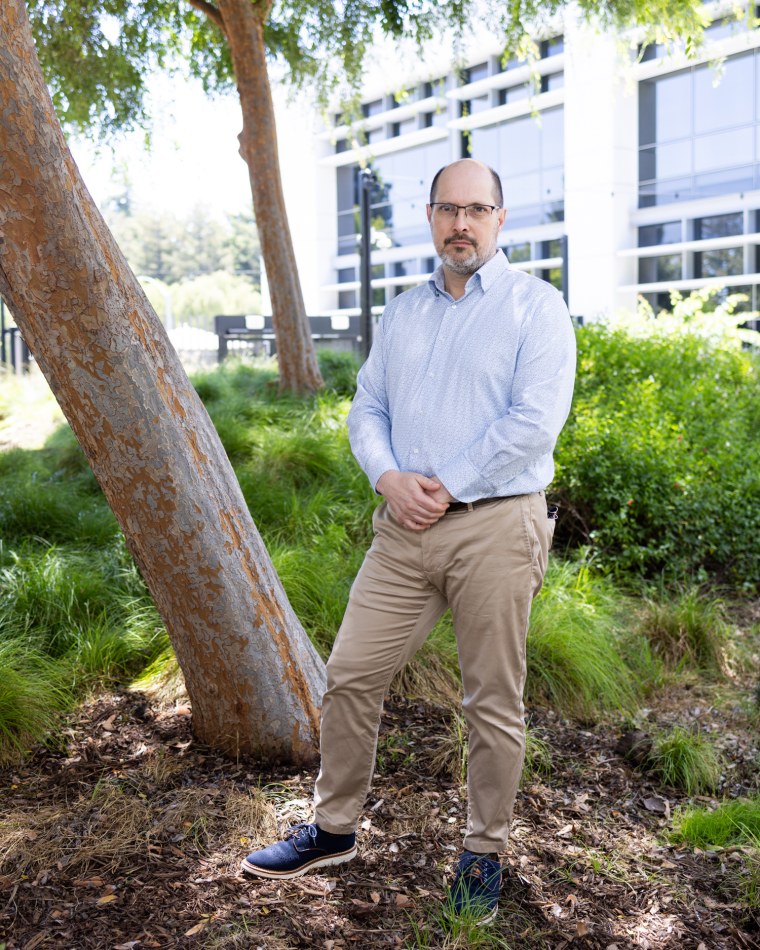 Joseph South stands in a tree patch outside of a building