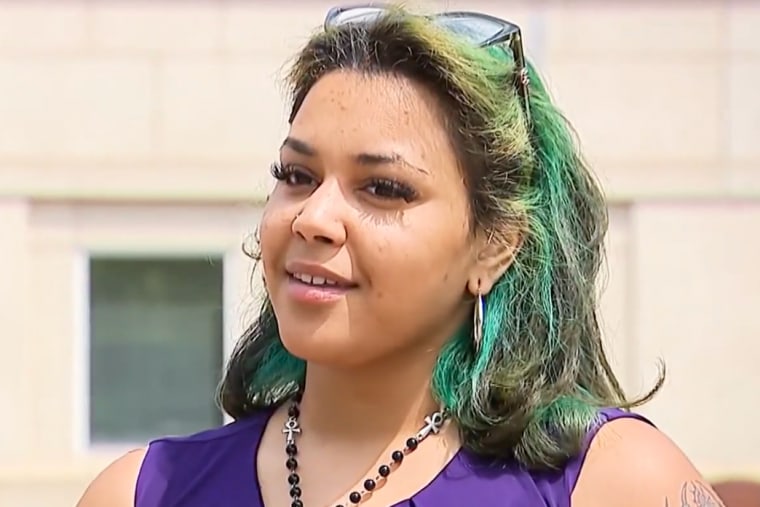 Kiany DeJesus speaks while standing outside in front of a building