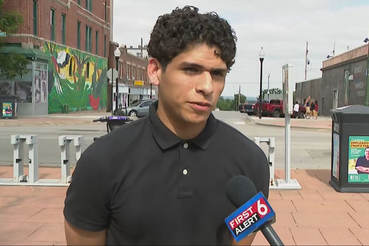 Luis Mejia speaks into a microphone being held in front of him