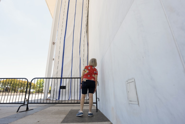 A woman gazes up at a large curtain obscuring the sign on the exterior of the Kennedy Center.