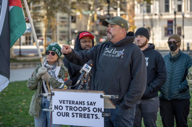 Bobby LaPin speaking at a lectern during an outdoor rally.
