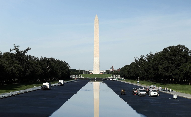 The Washington Monument rises above the horizon and is reflected in the water of the reflecting pool.