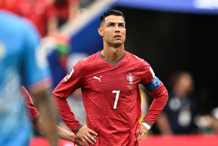 Cristiano Ronaldo stands on the soccer field with his hands on his hips, rolling his eyes