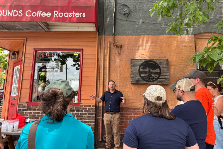 Bill Ferguson, standing in front of a brick wall, speaks to people outside