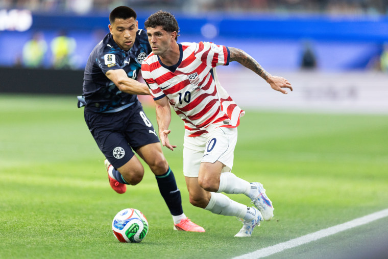 Christian Pulisic runs with the soccer ball while defended by Diego Gomez