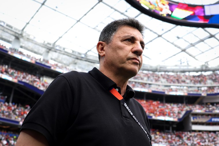 Amir Ghalenoei looks off while standing on the soccer field inside of a stadium