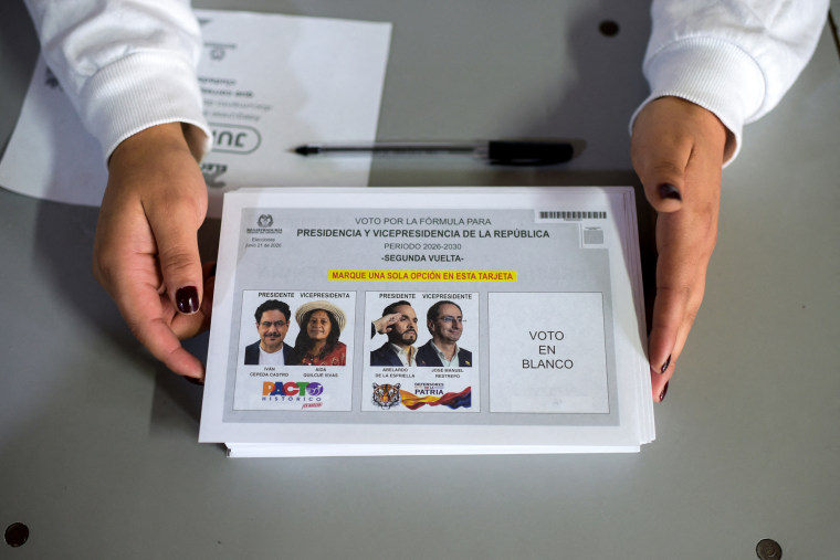 A worker holds electoral material on a table showing Colombian presidential candidates Iván Cepeda and Abelardo de la Espriella