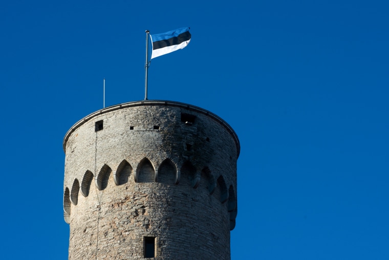 The Estonian flag is posted on top of the peak of a castle