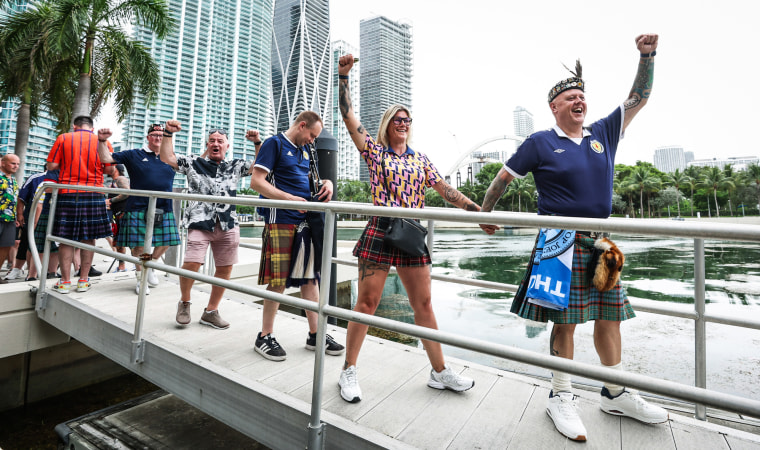 Fans in Tartan walk on a ramp by the water