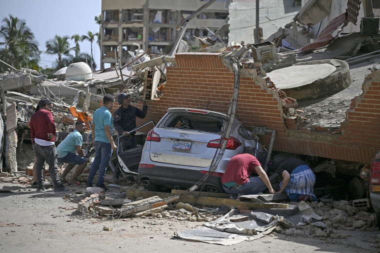People search through the rubble around a car trapped beneath the collapsed remains of a residential building following an earthquake in Venezuela