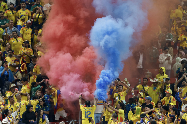 Red and blue smoke obscures fans of Colombia's national soccer team during a World Cup match.