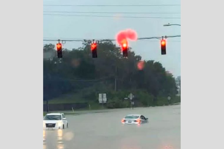 Submerged cars at an intersection with red lights.